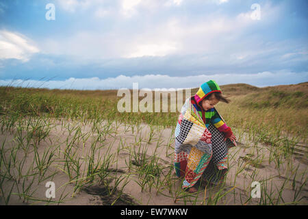 Girl on beach wrapped in a patchwork blanket