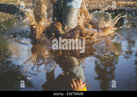 Close-up of child's legs splashing in a puddle of water, USA Stock Photo