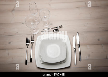 table set with plates, cutlery and glasses on wooden table Stock Photo