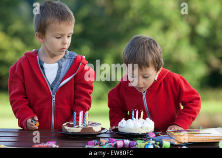 Two adorable boys with cakes, outdoor, celebrating birthday, having fun Stock Photo