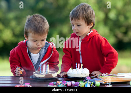 Two adorable boys with cakes, outdoor, celebrating birthday, having fun Stock Photo