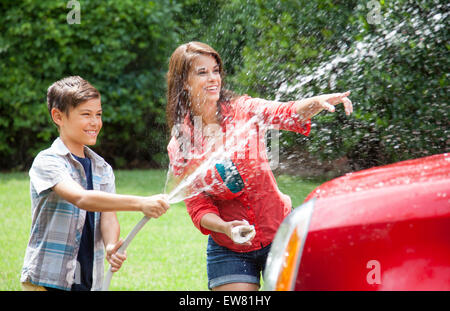 Family washing car together in driveway of home Stock Photo