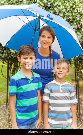 Single hispanic mother with two boys playing in the rain Stock Photo