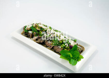 Spicy Thai Beef Salad with crispy rice and mint garnish. Stock Photo