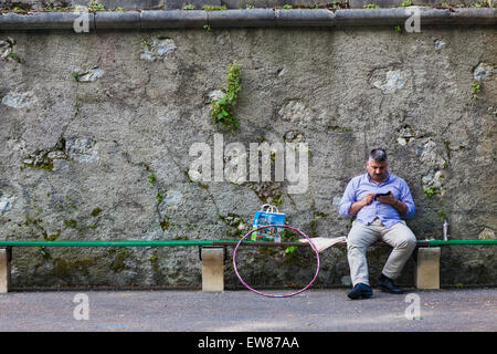 Older gentleman looking at his smart phone while siting on a bench Stock Photo