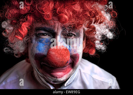 close up of a sad , upset , crying clown with a red nose on a black background Stock Photo