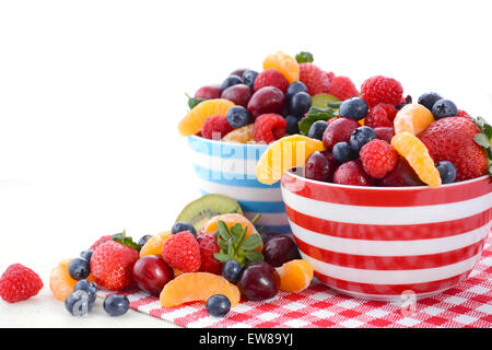 Fresh colorful fruit including raspberries, strawberries, cherries, blueberries, manadrines and kiwi fruit in breakfast bowls on Stock Photo