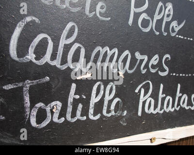black placard spanish white handwritten in wall with typical menu food dishes in Spain restaurant like squid and potato omelette Stock Photo