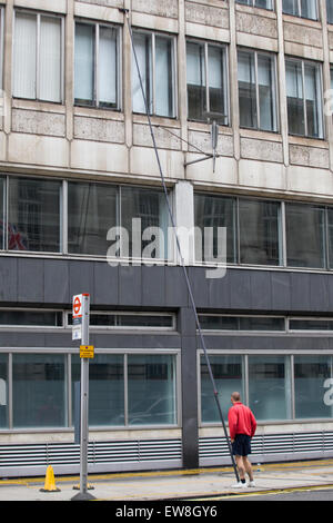 Man cleaning windows with a long pole in London Stock Photo