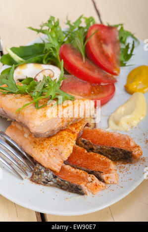 grilled fresh samon filet with vegetables salad tomato arugula mushroomsand paprika on top Stock Photo