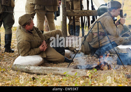 RUSSIA, BORODINO - OCTOBER 12: Unidentified soldiers resting near the fire on reenactment of the battle in WWII near the Borodino village in 1941, in Moscow region, Borodino, on 12 October, 2014, Russia Stock Photo