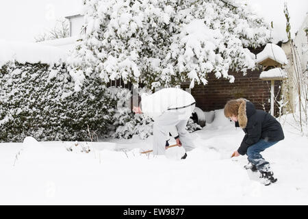 Father and son shoveling snow together in a garden Stock Photo