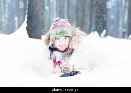 Portrait of a cute smiling child digging in the snow Stock Photo