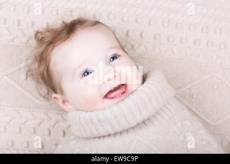 Cute funny baby girl in a knitted sweater on a knitted blanket Stock Photo