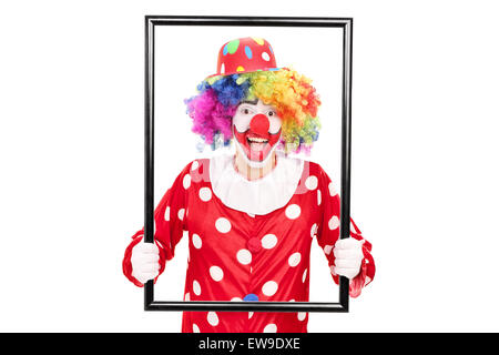 Male clown holding a big picture frame and posing behind it isolated on white background Stock Photo