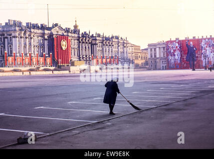 April 30, 1984 - Leningrad, Russia - In early morning a Russian woman sweeps the Palace Square, the central city square of Leningrad (St. Petersburg). In background the faÃ§ade of the Winter Palace, part of the Hermitage Museum, is decorated for the annual May Day Parade with reviewing stands and portraits of the Central Committee of the Communist Party of the USSR. At right a giant banner with an image of Vladimir Lenin, Communist revolutionary and first leader of the USSR, covers a building faÃ§ade. (Credit Image: © Arnold Drapkin/ZUMA Wire) Stock Photo