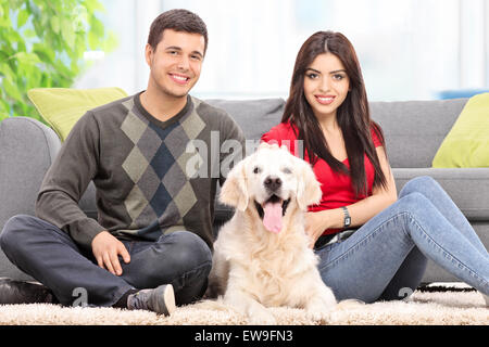 Young couple sitting on the floor with a dog at home Stock Photo