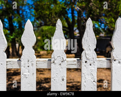 Detail of old white picket fence with layers of paint that has collected over many years. Stock Photo