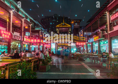 People eating outside surrounded by neon lights Stock Photo