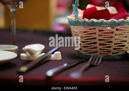 Decorative flower petals in a bamboo basket on a dinning table top setup. Stock Photo