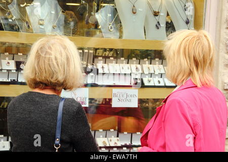 Two women peruse jewelery made with Blue John stone through a shop window in Castleton, Peak District, England UK Stock Photo