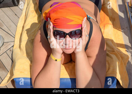 Young plump woman is lying on her stomach in sunlight for a tan. Stock Photo