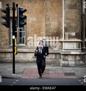 Three Asian men walk across a pedestrian crossing in Cambridge city centre in single file Stock Photo