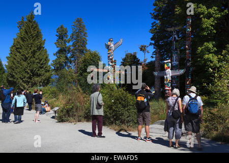 Visitors viewing and capturing images of the totem pole display at Brockton Point in Stanley Park  - Vancouver, British Columbia Stock Photo