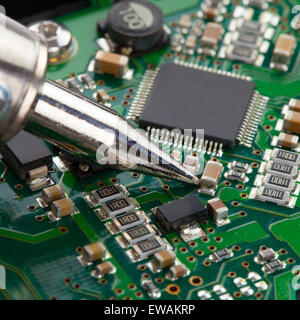 Soldering iron with microcircuit - close up shot Stock Photo