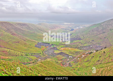 Lanzarote, Canary Islands, Spain. A view from a mountain to a fertile green valley with plantations on the hillsides and small h Stock Photo