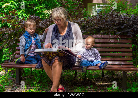 Grandmother reading to her grandchildren in the park Stock Photo