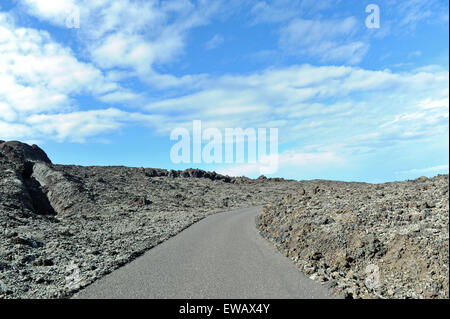 Lanzarote, Canary Islands, Spain. An asphalt road in the middle of a volcanic plain, taking a curve in the horizon.