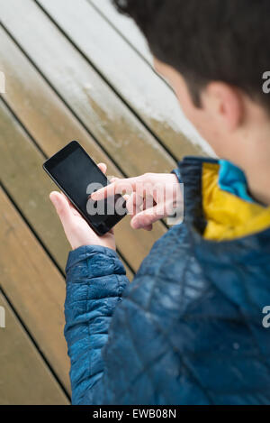 Young adult using an smartphoe. Man is touching the screen. Stock Photo