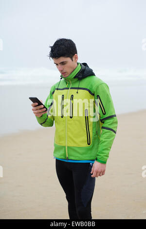Runner man rest and looking his smartphone in the beach in a rainy day. Stock Photo