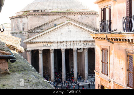 Windows of historical building in the center of Rome and view of the Pantheon, columns and pediment, while people entering Stock Photo