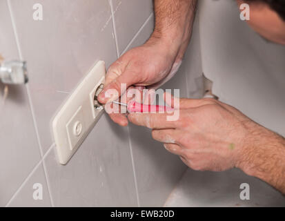 electrician repairing a socket at home Stock Photo