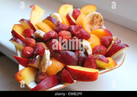 colorful strawberries, banana, peach and red plum cut on slices for  fruit salad Stock Photo