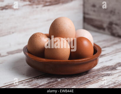 Eggs inside a clay plate over wooden background in a studio shot Stock Photo