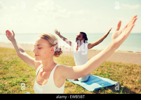 smiling couple making yoga exercises outdoors Stock Photo