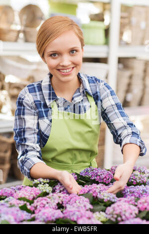 happy woman taking care of flowers in greenhouse Stock Photo