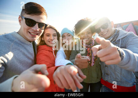 happy teenage friends pointing fingers on street Stock Photo