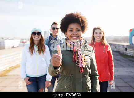 happy teenage friends showing thumbs up on street Stock Photo