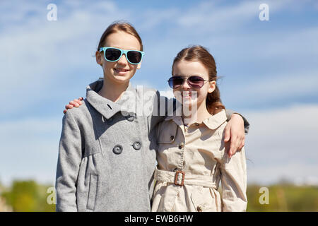 happy little girls in sunglasses hugging outdoors Stock Photo
