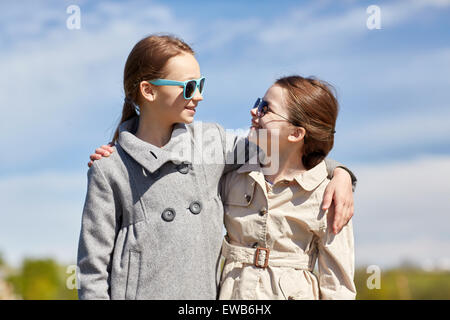 happy little girls hugging and talking outdoors Stock Photo