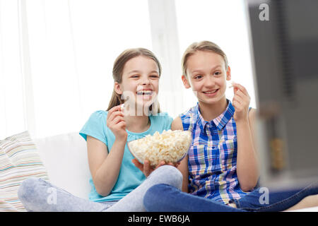 happy girls with popcorn watching tv at home Stock Photo