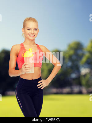 smiling sporty woman with protein shake bottle Stock Photo