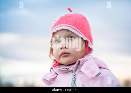 Cute Caucasian blond baby girl in pink hat, outdoor closeup portrait Stock Photo