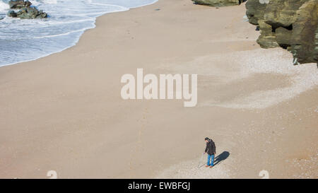 Man using metal detector on beach in Devon, UK Stock Photo