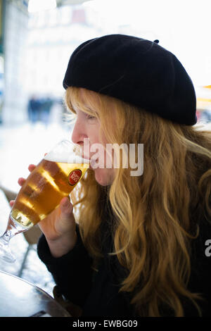 woman with red hair and beret drinking glass of beer Stock Photo