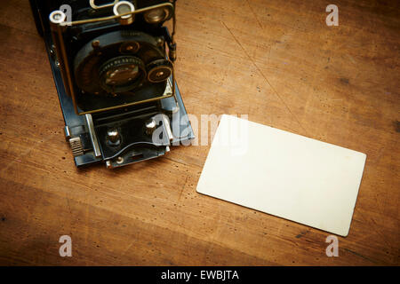 Vintage old retro film camera and old empty paper frame photos on wooden background. Nostalgic style picture, memories, Stock Photo